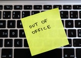 Image of a post-it note stuck to an office keyboard with the words 'OUT OF OFFICE' written on it