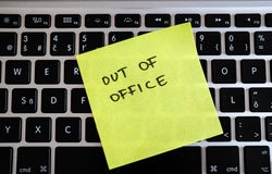 Image of a post-it note stuck to an office keyboard with the words 'OUT OF OFFICE' written on it