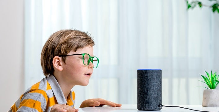 Voice controlled smart speaker. Little kid girl talking to talking to Amazon Alexa Echo Dot. Education programme for child. Boy talking to Alexa and give it orders and commands what to switch on