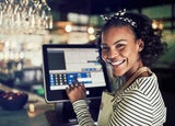 Mid shot of POS system on counter in a restaurant with female worker smiling and entering numbers