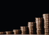 growing piles of gold coins on a table with a black background