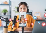 Vlogger live streaming podcast review on social media, Young Asian woman use microphones wear headphones with laptop record video. Content creator concept.