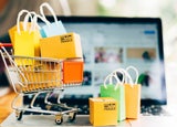 mini shopping trolley full of bags on a computer keyboard