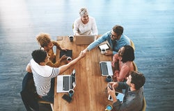 Handshake, above and business people in a meeting for a deal, onboarding and welcome. Happy, interview and corporate employees shaking hands for thank you, support or partnership in group discussion