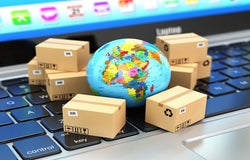 Small globe on a keyboard surrounded by small brown packages