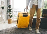 People getting ready for holidays travel trip concept. Single traveller man walking carry a luggage begin a journey. Men wear casual cloth and sneakers. Background in living room at home or hotel.