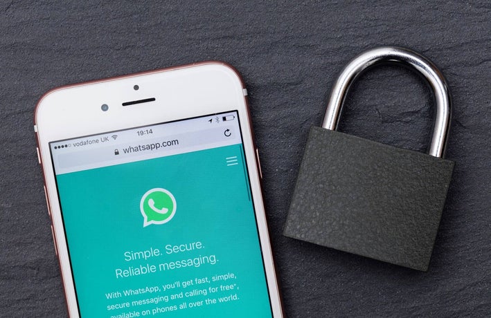 WhatsApp open on a smartphone next to a padlock