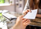 Person giving a cheque to their colleague