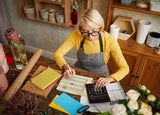 High angle portrait of female businesswoman counting finances using calculator in small shop, copy space