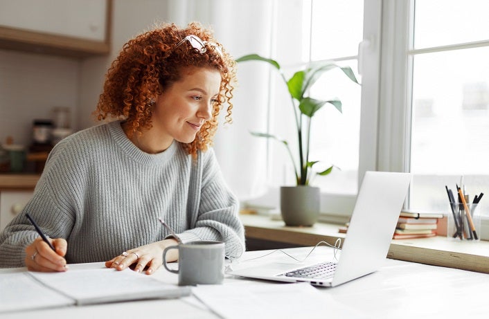 Small business owner researches business software and technology at her kitchen table