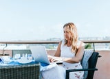 a woman working at a laptop in a sunny climate