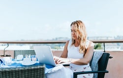 a woman working at a laptop in a sunny climate