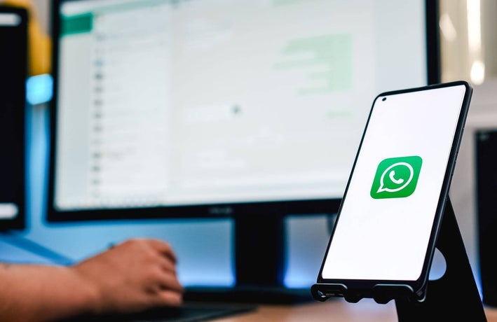Person using WhatsApp on a web browser with WhatsApp on a mobile in the foreground
